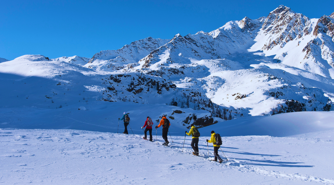 Nesta imagem, é possível observar pessoas a praticar montanhismo na neve. 