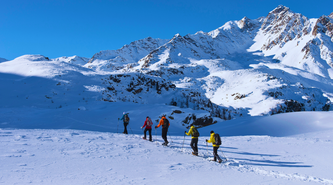 Nesta imagem, é possível observar pessoas a praticar montanhismo na neve.